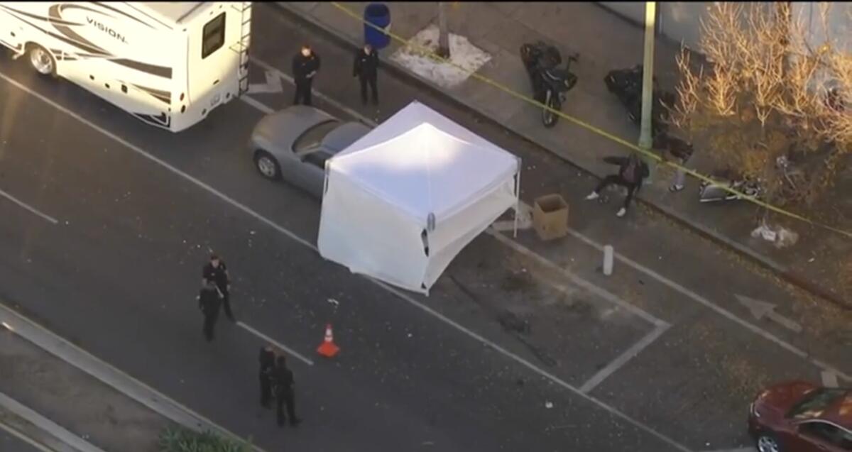 A white tent sits on one lane of a road partly covering a car.