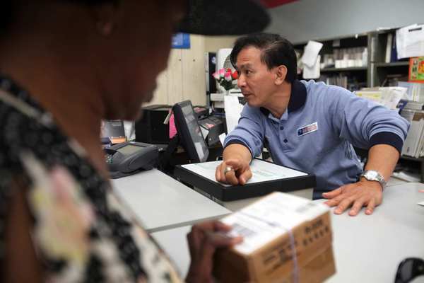 Postal worker Raymond Tran, right, 48, helps customers at the Little Saigon post office. Tran is something of an institution himself, assigned here since 1991. Nobody calls him by his last name -- it's just Raymond.