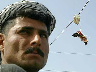 An Iraqi man stands close to a charred human limb tied to a brick thrown onto a power line in Fallouja.