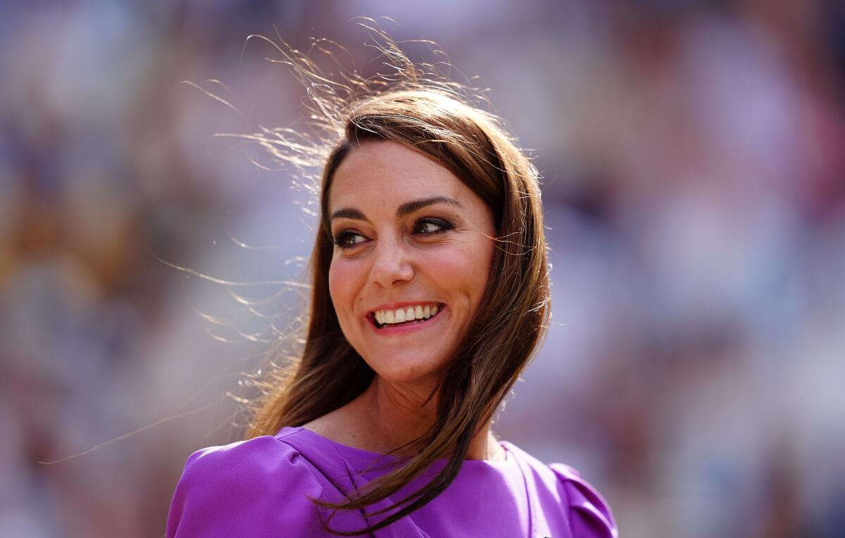 Catherine, Princess of Wales, smiling and looking over her shoulder in an electric purple dress