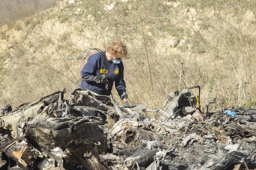 In this image taken Monday, Jan. 27, 2020, and provided by the National Transportation Safety Board, NTSB investigator Carol Hogan examines wreckage as part of the NTSB’s investigation of a helicopter crash near Calabasas, Calif. The Sunday, Jan. 26 crash killed former NBA basketball player Kobe Bryant, his 13-year-old daughter, Gianna, and seven others (James Anderson/National Transportation Safety Board via AP)