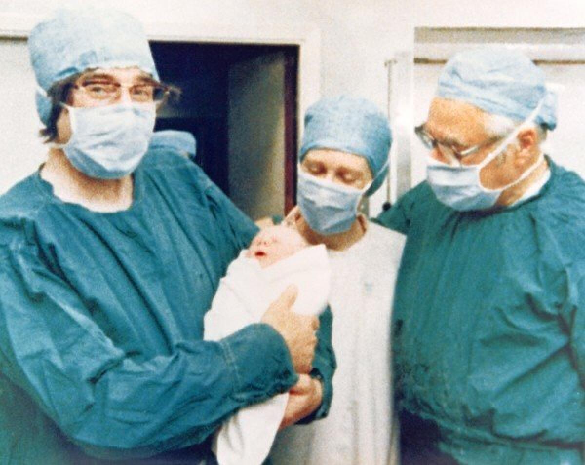 Robert Edwards holds the world's first "test-tube baby," Louise Joy Brown. She was the first infant born from an egg fertilized outside the human body.