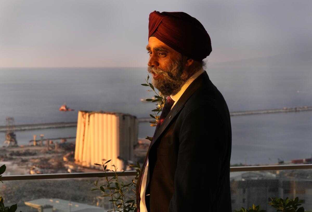 Canadian Minister of International Development Harjit Sajjan, stands on the balcony of the Canadian ambassador residence, as he was looking to the seaport Silos which damaged during the Beirut's massive explosion in August 2020, in Beirut, Lebanon, Wednesday, Aug. 17, 2022. Sajjan said Syria is not safe yet for millions of refugees to start returning home and those who fled their homes did so only because they had to. He also said , he also said that Lebanon should work to reach a deal with the International Monetary Fund to start getting the small nation out its worst economic crisis in its modern history. (AP Photo/Hussein Malla)