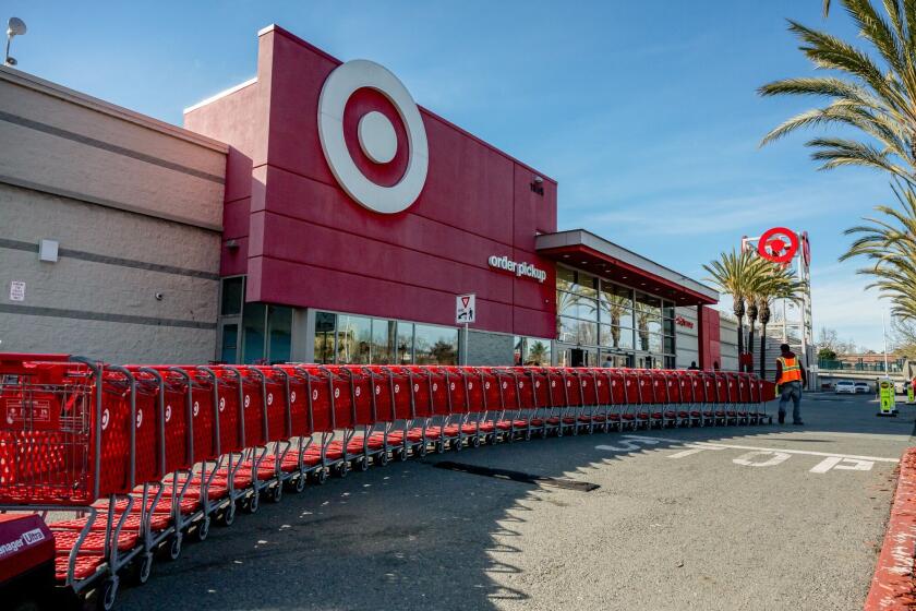 A worker moves shopping carts outside a Target store in Emeryville, California. Photographer: David Paul Morris/Bloomberg