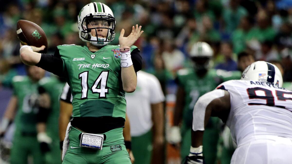 Marshall quarterback Chase Litton (14) is pressured by Connecticut defensive lineman Kenton Adeyemi (95) as he throws a touchdown pass in the first quarter Saturday.
