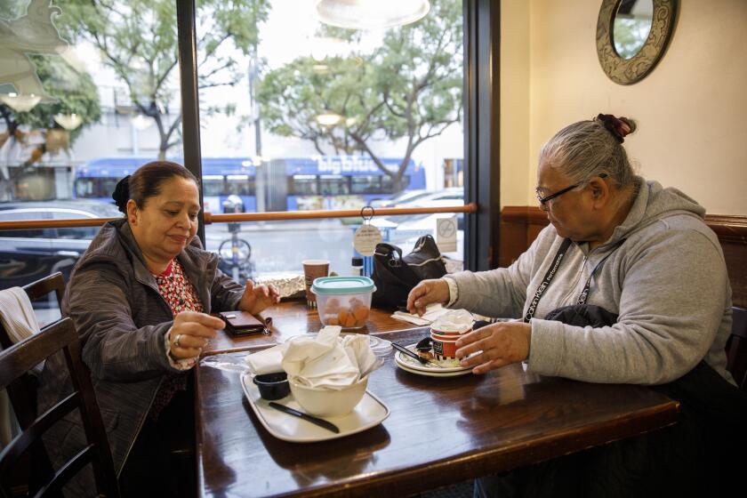 Sonia Esperanza Valencia, left, and Dora Mayen, who work as housekeepers, meet for morning coffee together at a cafe near UCLA before heading out to work homes on Friday, March 13, 2020 in the Westwood neighborhood of Los Angeles, Calif. The fears of the coronavirus has already caused some domestic workers to lose work. (Patrick T. Fallon/ For The Los Angeles Times)