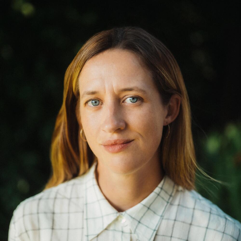 A filmmaker in a button-down top poses for the camera.