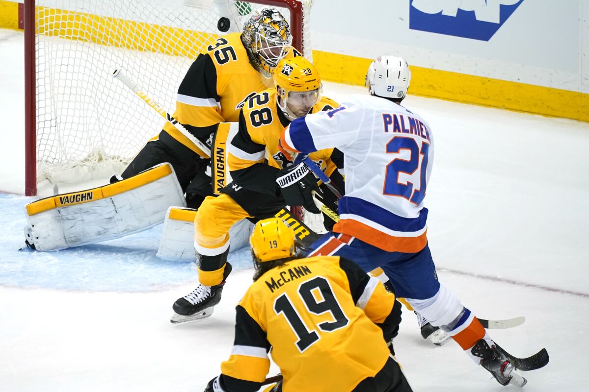 New York Islanders' Kyle Palmieri (21) puts a shot over Pittsburgh Penguins goaltender Tristan Jarry (35) with Marcus Pettersson (28) defending for the game-winning goal in overtime in Game 1 of an NHL hockey Stanley Cup first-round playoff series in Pittsburgh, Sunday, May 16, 2021. The Islanders won 4-3. (AP Photo/Gene J. Puskar)