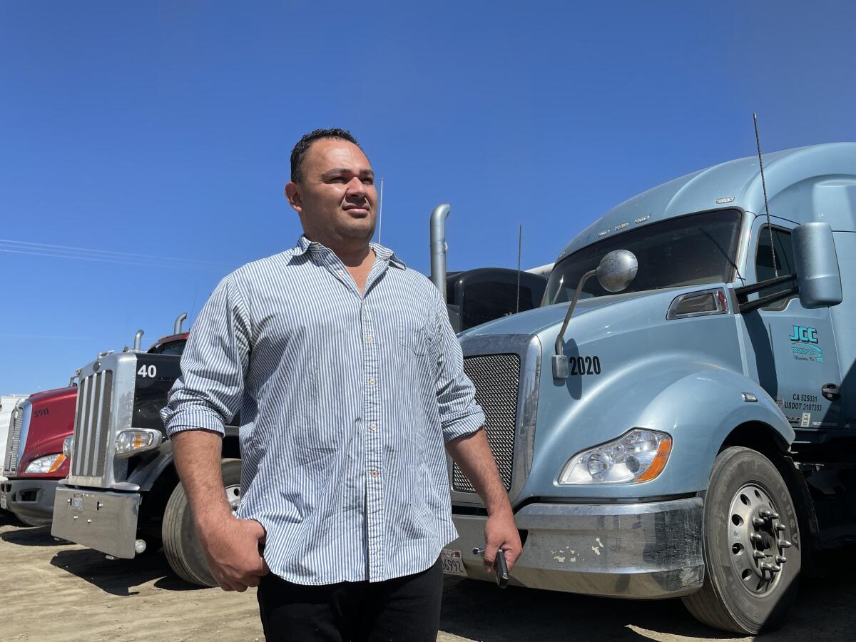 A man stands near a row of large trucks.