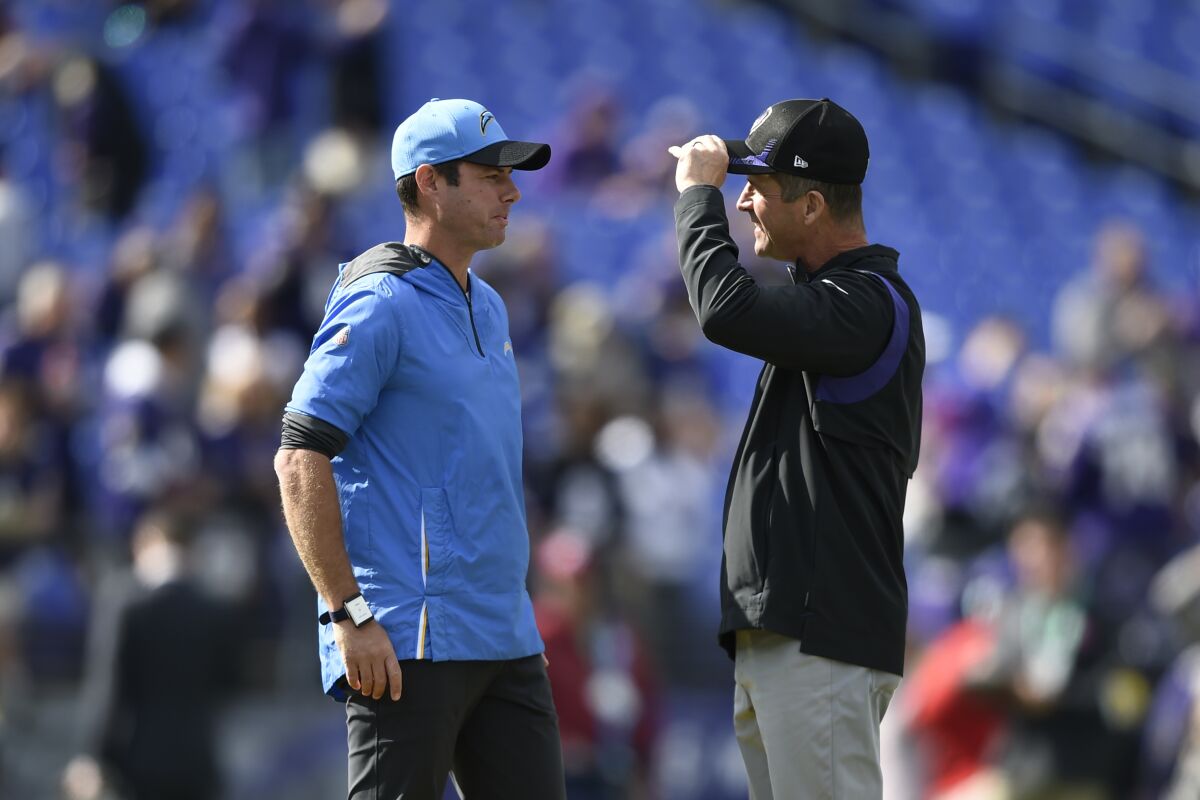 Chargers head coach Brandon Staley, left, talks with Baltimore Ravens head coach John Harbaugh.