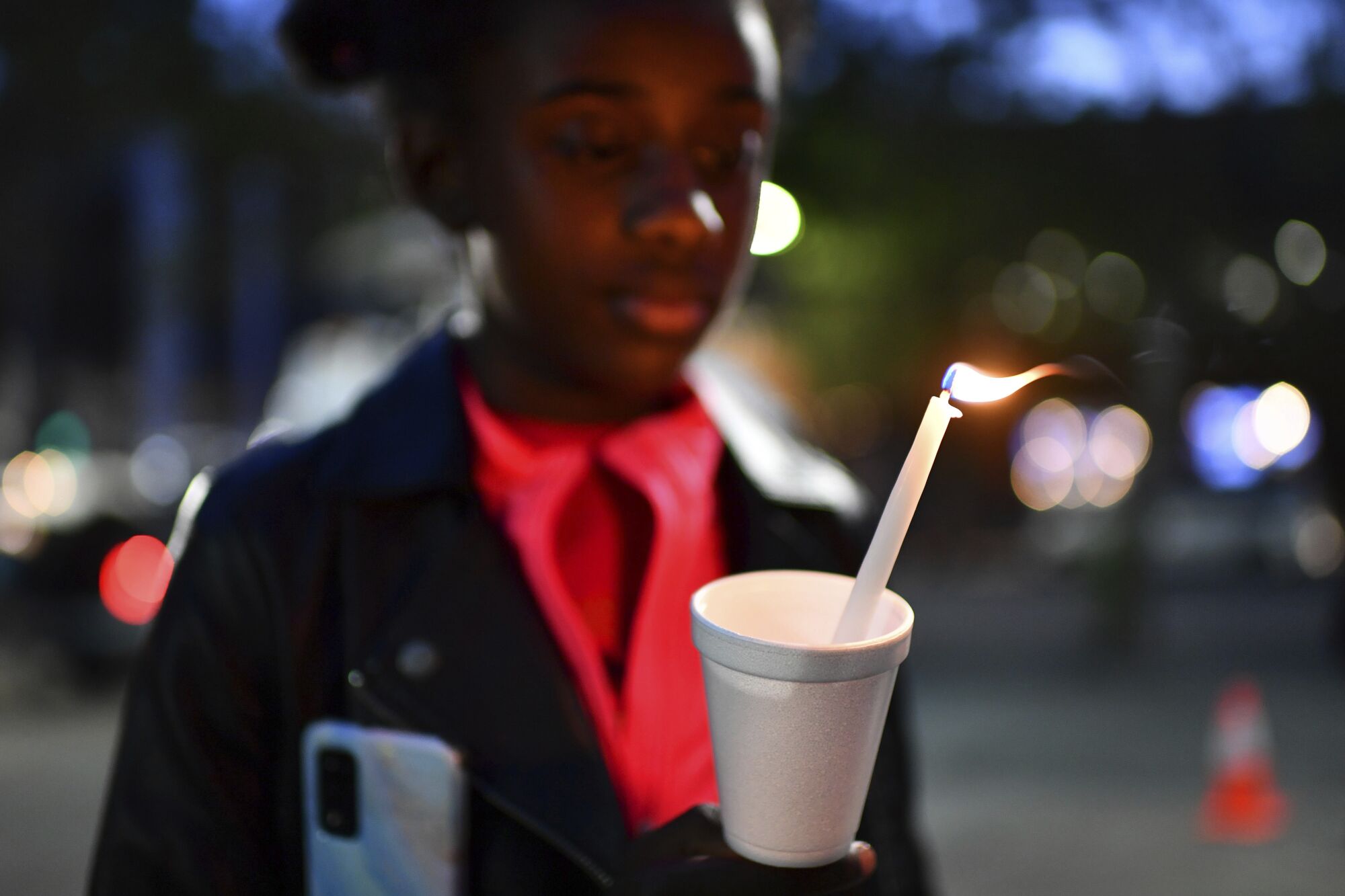 Gabrielle Knox, 9, of Sacramento, holds a candle during a vigil at Ali Youssefi Square in Sacramento