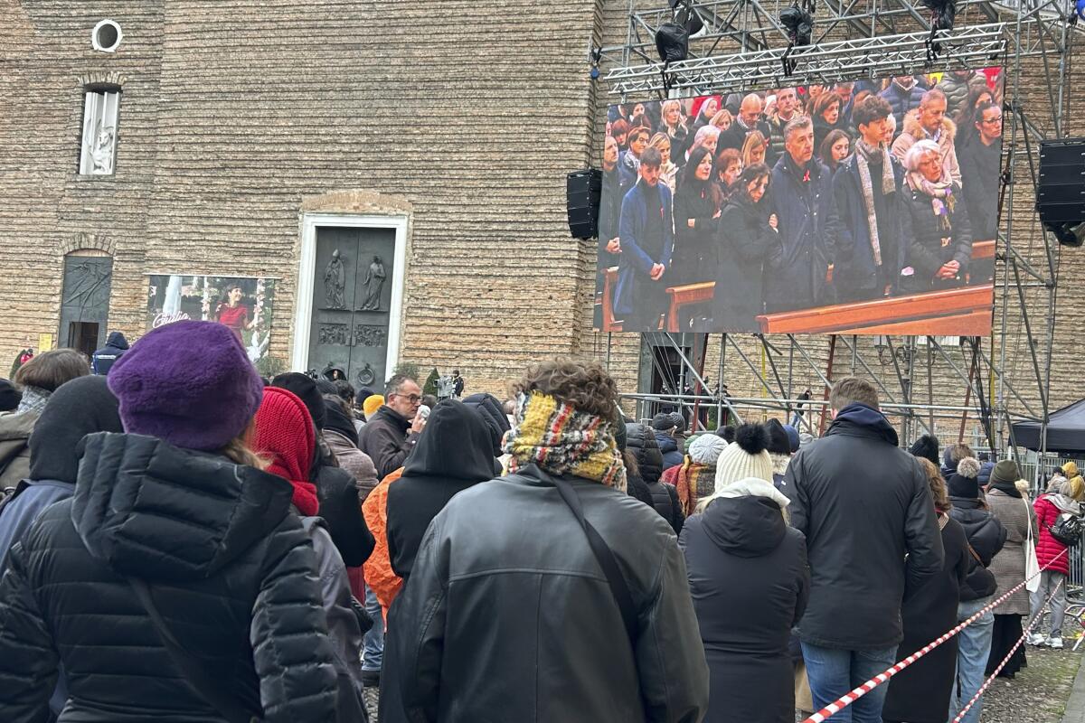 Gente observa en una pantalla el funeral de Giulia Cecchettin, frente a la iglesia de Santa Giustina