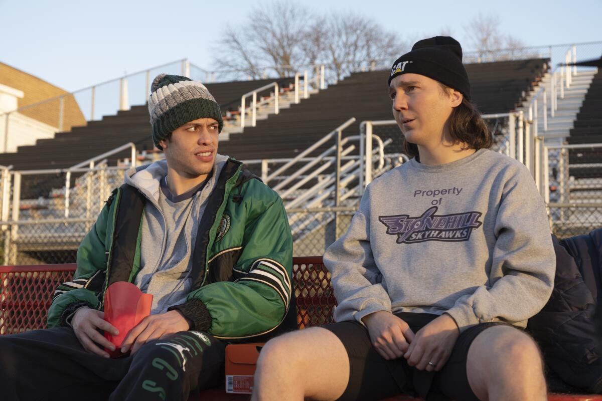 Two men sitting on the bleachers in winter clothing.