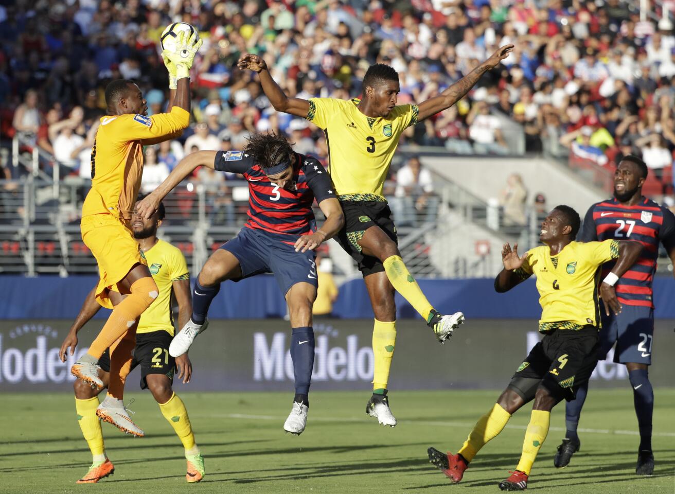 Jamaica goalkeeper Dwayne Miller, left, catches the ball over Damion Lowe, right, and United States' Omar Gonzalez, center, during the first half of the Gold Cup final soccer match in Santa Clara, Calif., Wednesday, July 26, 2017. (AP Photo/Marcio Jose Sanchez)