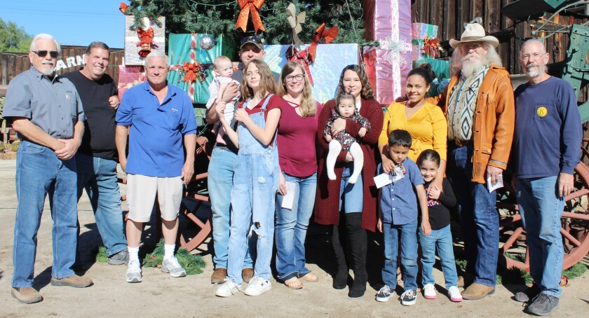 Kiwanis Club of Ramona members gather in front of the Christmas tree with military families accepting donations.