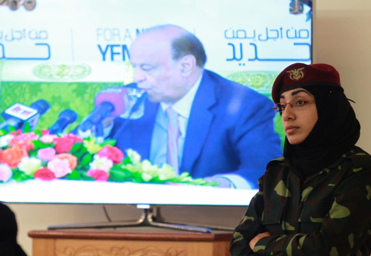 A Yemeni policewoman stands guard as an image of President Abdu Rabu Mansour Hadi is seen on a screen during a security conference in Sana.