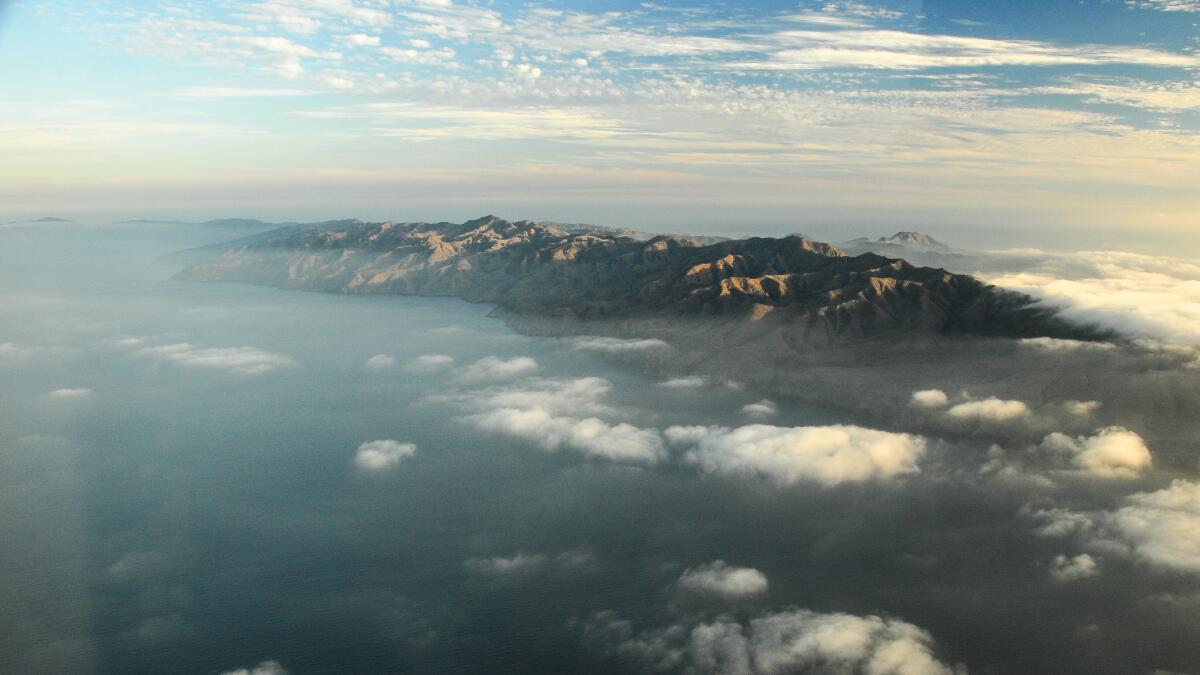 An aerial view of Santa Cruz Island shows its mountainous landscape surrounded by ocean.