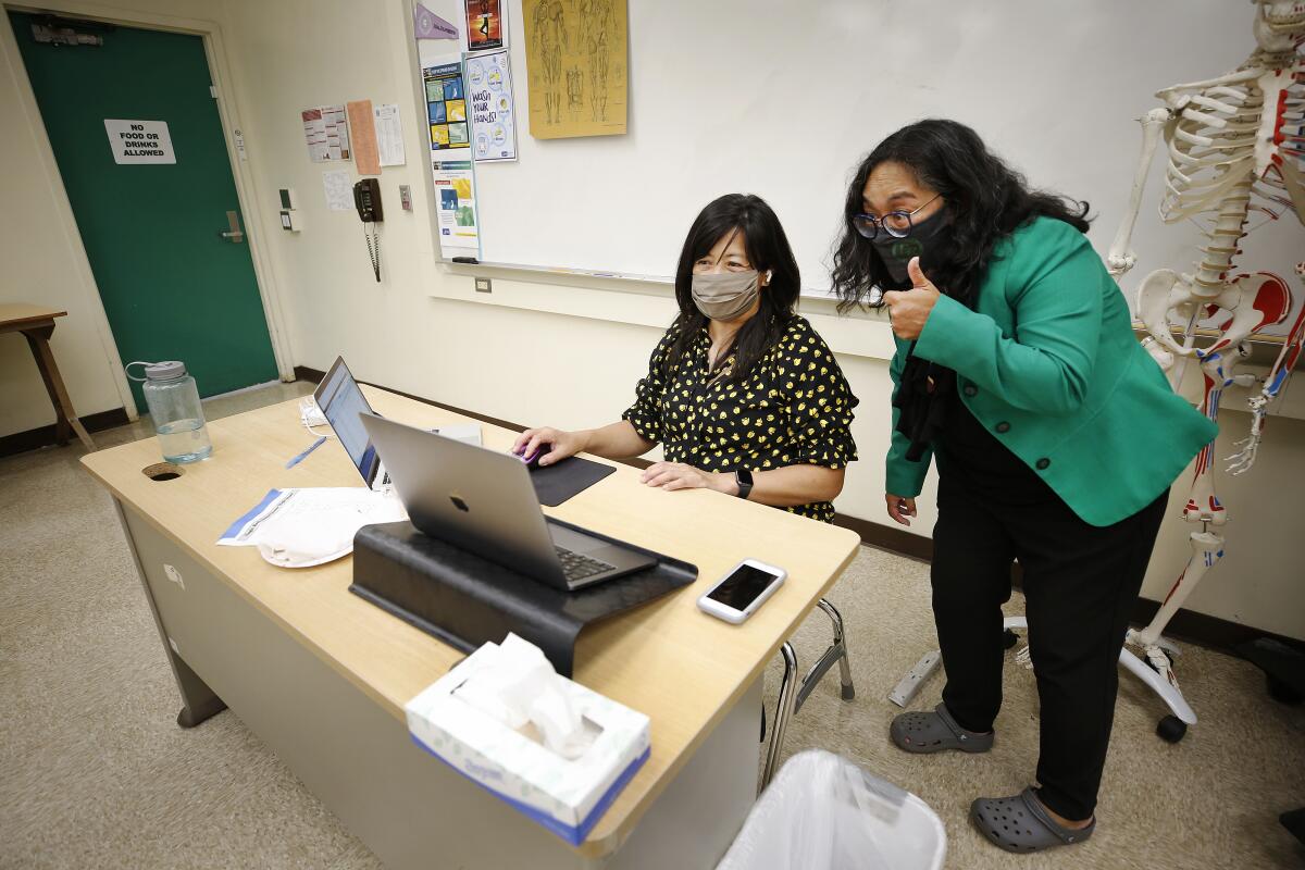 The principal and a teacher from Eagle Rock Jr./Sr. High School look at a computer during an online class.