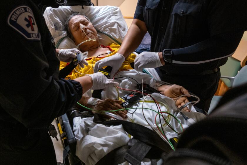 Los Angeles, CA - March 23: EMT's Meagan Parker, left, and Daniel Avena, right, buckle Ernesto Chavez, middle, onto a gurney. Chavez is a patient at MLK Community Hospital on Thursday, March 23, 2023, in Los Angeles, CA. He is being transferred. (Francine Orr / Los Angeles Times)