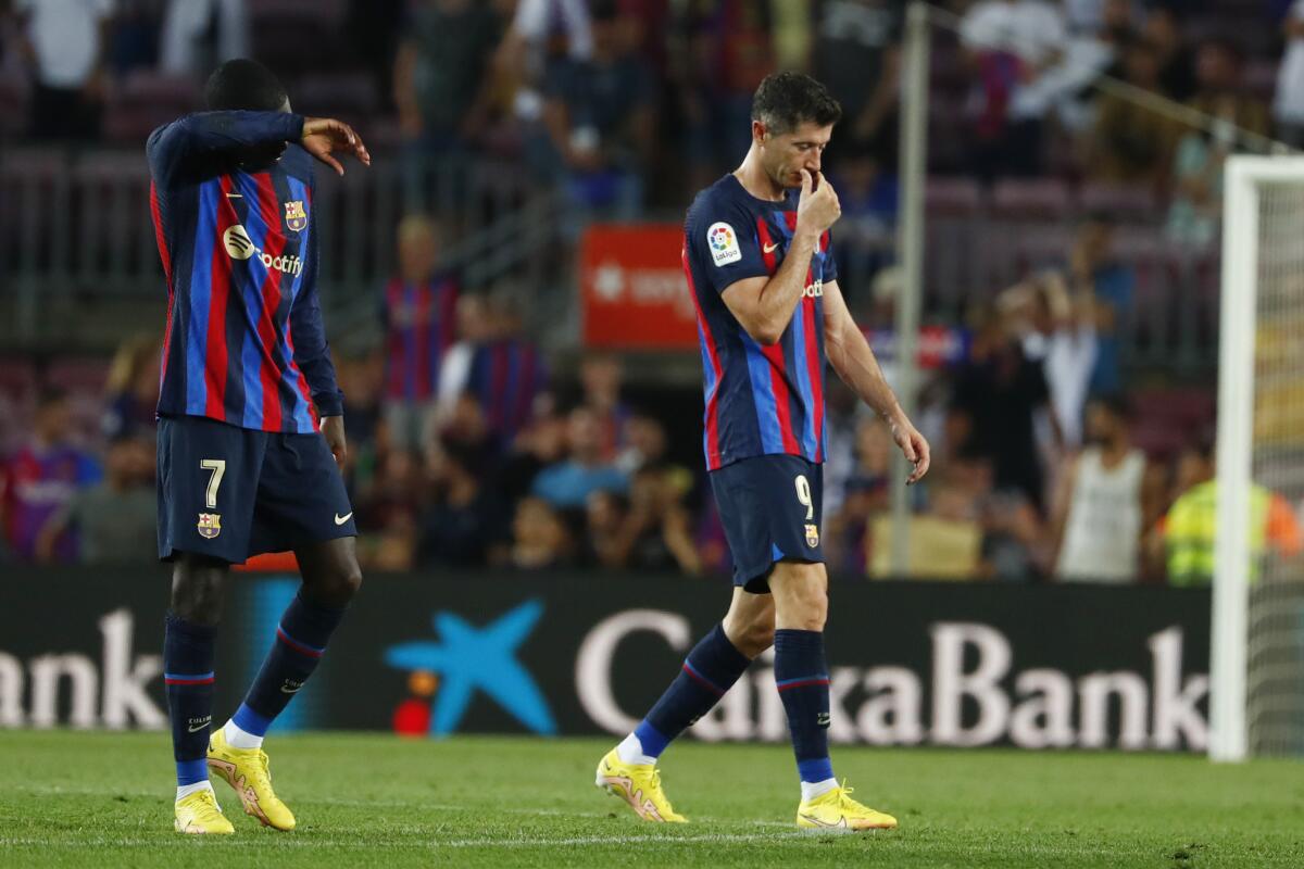 Barcelona's Ousmane Dembele, left and Barcelona's Robert Lewandowski walk off the pitch at the end of a Spanish La Liga soccer match between Barcelona and Rayo Vallecano at the Camp Nou stadium in Barcelona, Spain, Saturday, Aug. 13, 2022. (AP Photo/Joan Monfort)