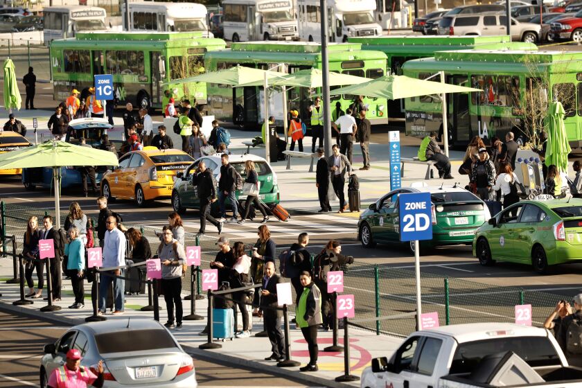 LOS ANGELES CA OCTOBER 29, 2019 — Passengers walk or can take a shuttle to the new passenger pickup lot Tuesday, October 29, 2019, the first day to connect with Uber, Lyft and taxis that are no longer allowed to pick up arriving passengers at terminals. (Al Seib / Los Angeles Times)