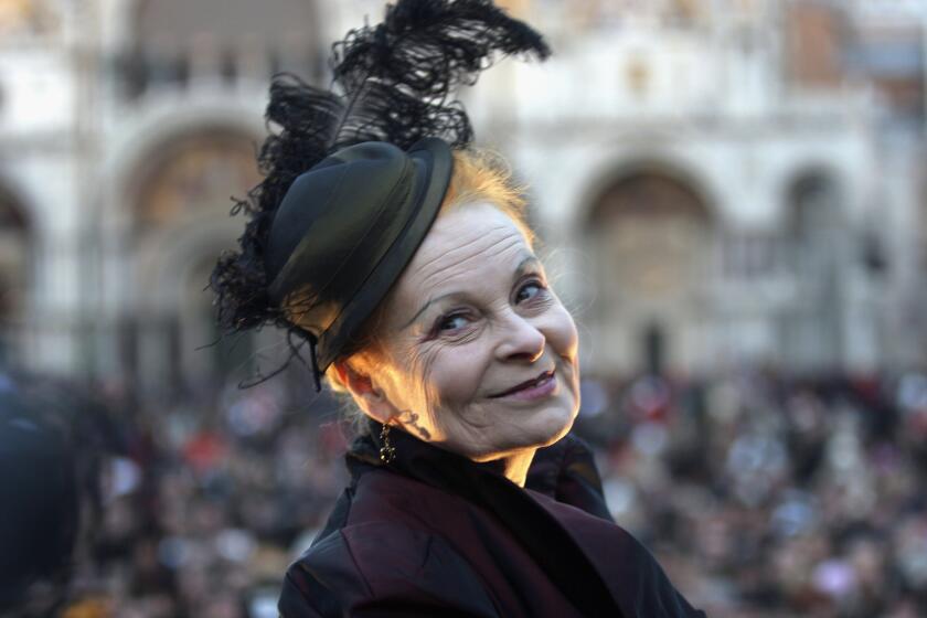 English designer Vivienne Westwood wearing a small black hat with a feather.