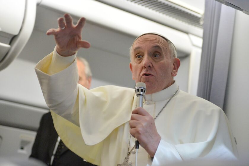 Pope Francis answers questions during a news conference aboard the papal flight on the journey back from Brazil on Monday.
