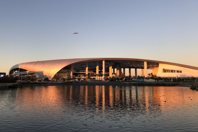 SoFi Stadium's gently curving roof seem to curl into the water of the lake in Lake Park