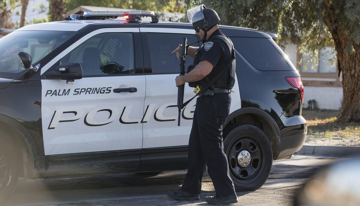 A Palm Springs police officer holding a shotgun next to a police SUV in 2016