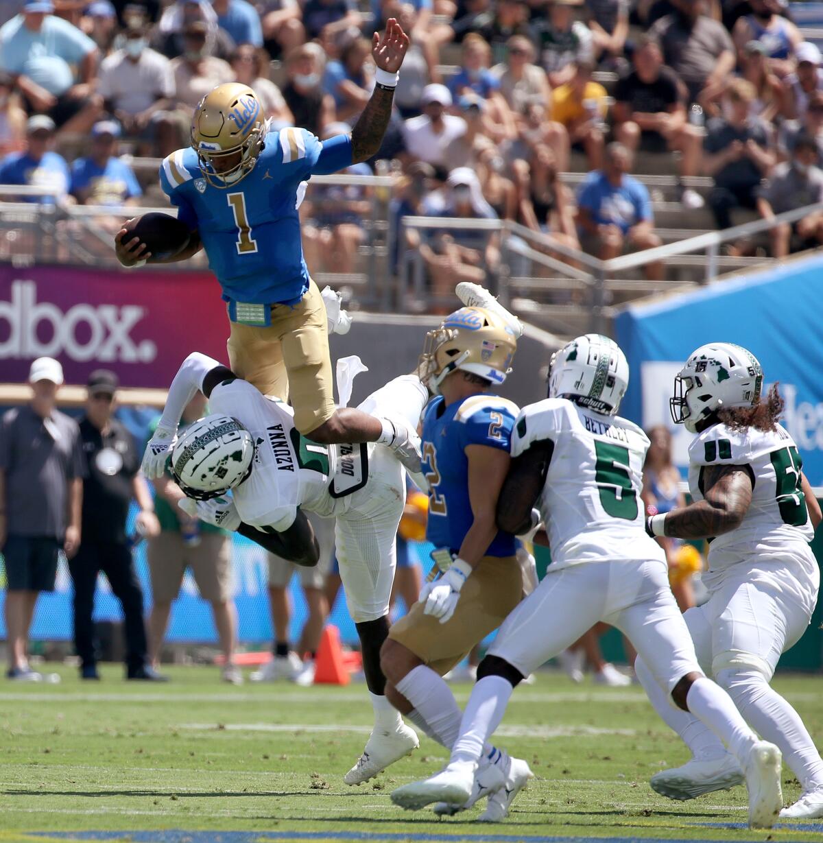 UCLA quarterback Dorian Thompson-Robinson tries to hurdle over Hawaii defender Chima Azunna in the first quarter Saturday.