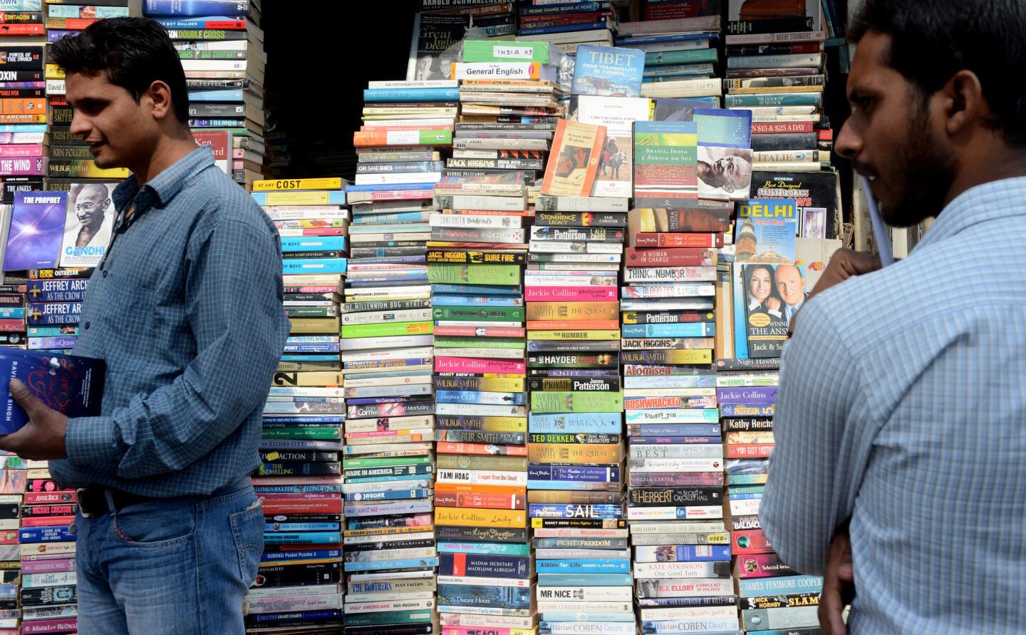 Shoppers browse books in multiple languages at an outdoor stall in New Delhi.