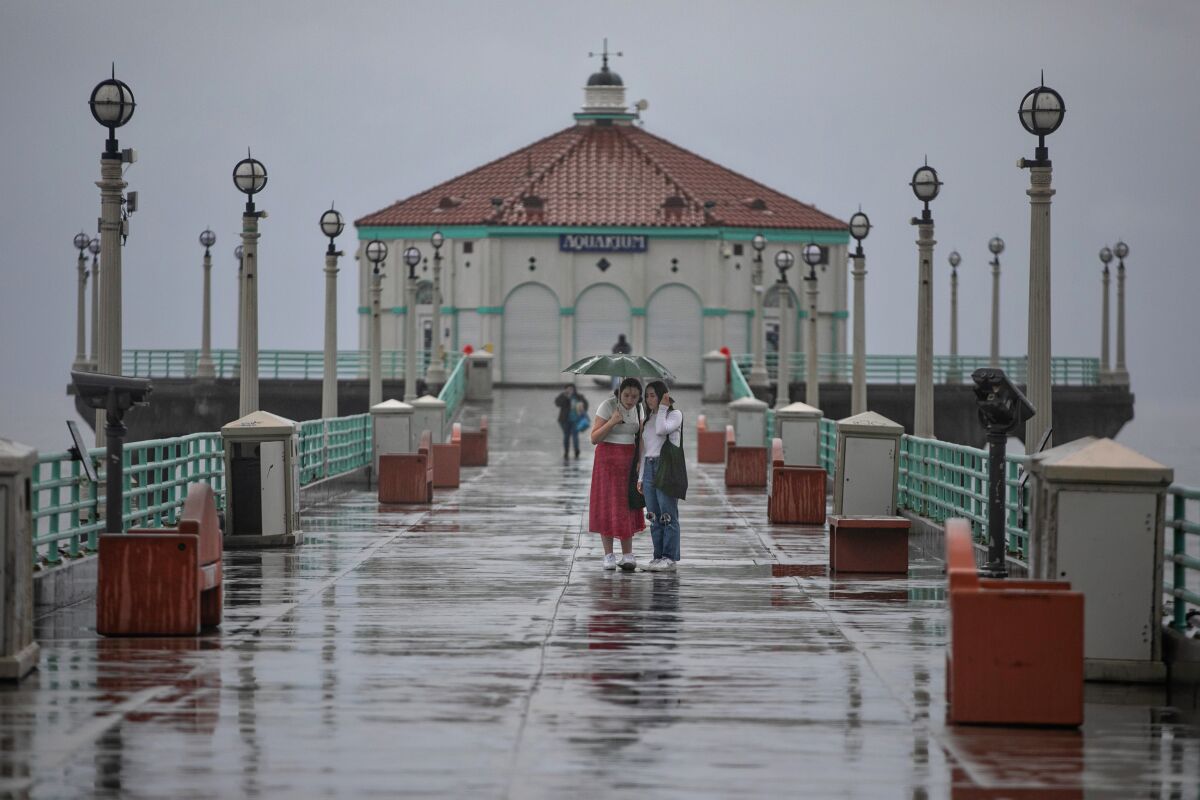 Two women walk in the rain on the Manhattan Beach Pier earlier this year.