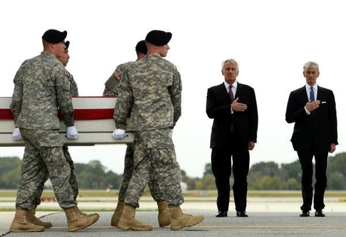 Secretary of Defense Chuck Hagel and Secretary of the Army John McHugh stand by as soldiers carry the flag-draped transfer case containing the remains of U.S. Army Pfc. Cody J. Patterson at Dover Air Force Base.