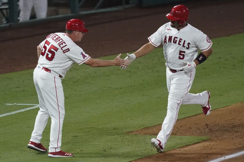 Los Angeles Angels' Albert Pujols, right, is greeted by third base coach Brian Butterfield.