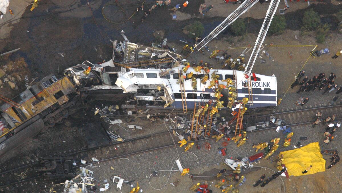 Aerial view of firefighters and rescuers around the wreckage of two trains on their sides after a head-on collision