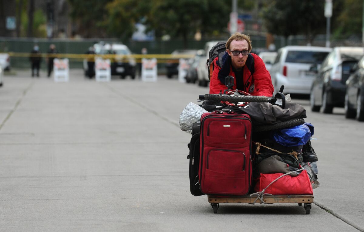 A man moves his belongings away from Echo Park Lake before LAPD officers evict the homeless people living there.