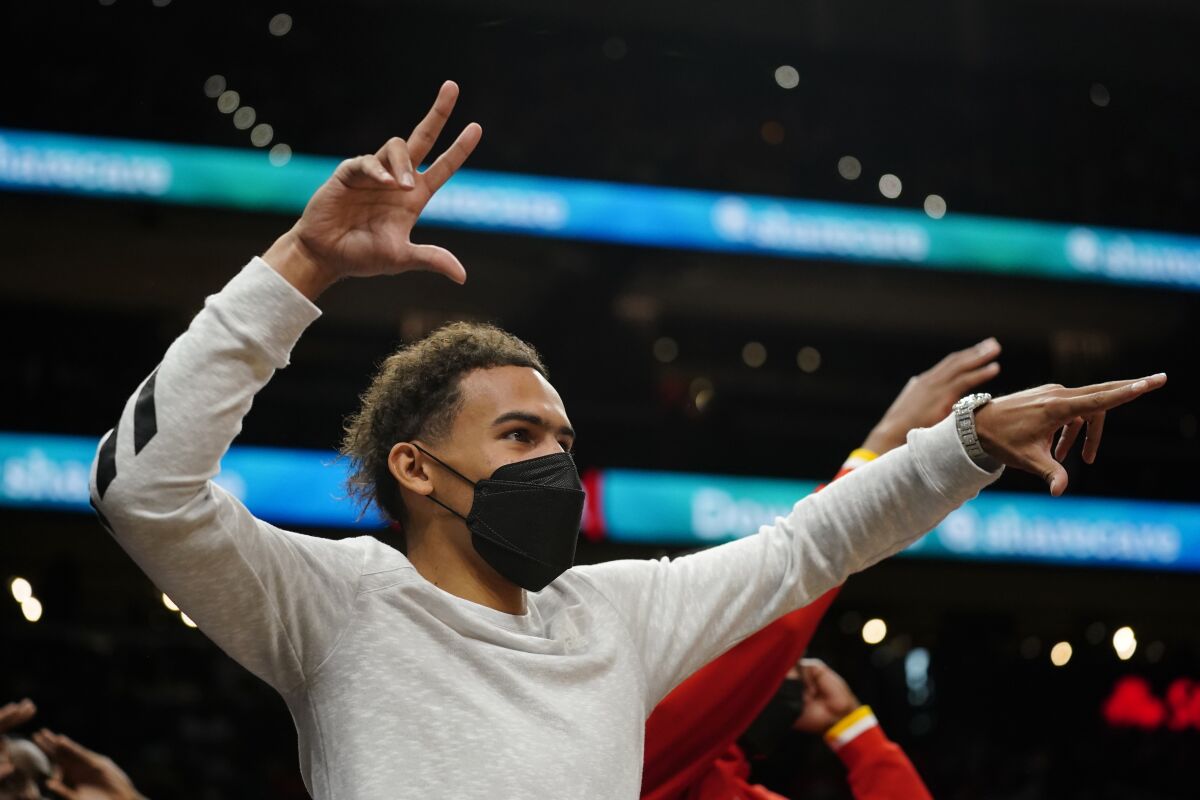 Injured Atlanta Hawks guard Trae Young reacts on the bench after an Atlanta basket against the Cleveland Cavaliers during the second half of an NBA preseason basketball game Wednesday, Oct. 6, 2021, in Atlanta. (AP Photo/John Bazemore)