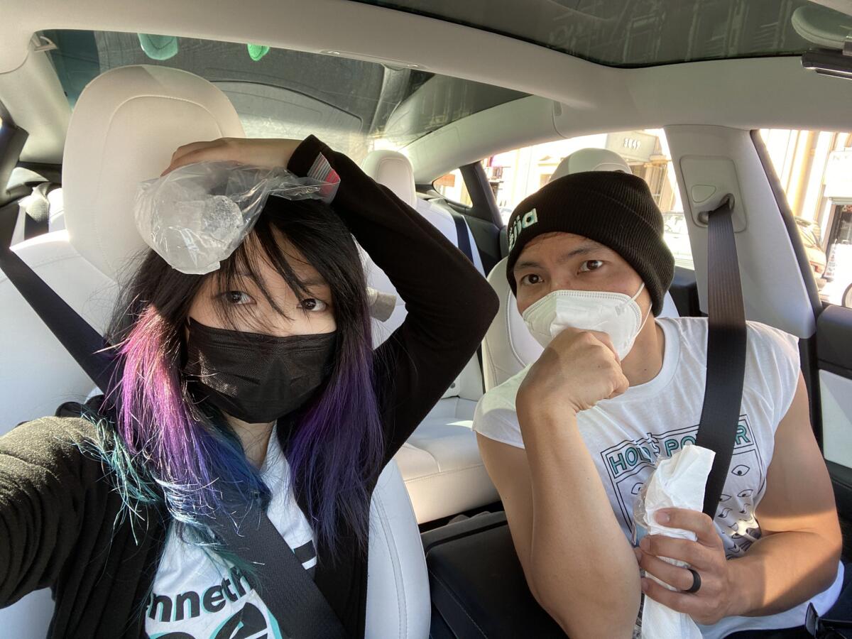 A woman holding ice on her head next to a man in a car