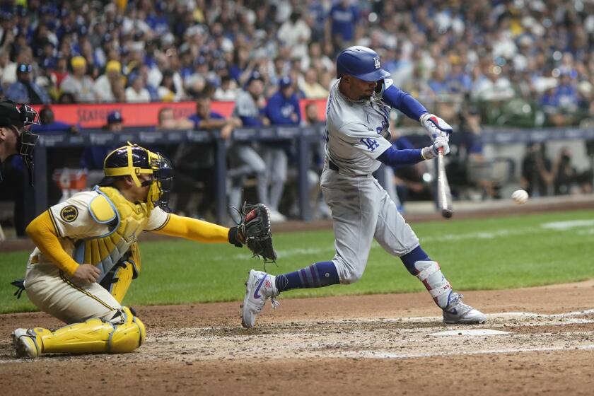 Mookie Betts, derecha, de los Dodgers de Los Ángeles, batea un sencillo productor durante la séptima entrada del juego de béisbol en contra de los Cerveceros de Milwaukee, el lunes 12 de agosto de 2024, en Milwaukee. (AP Foto/Aaron Gash)