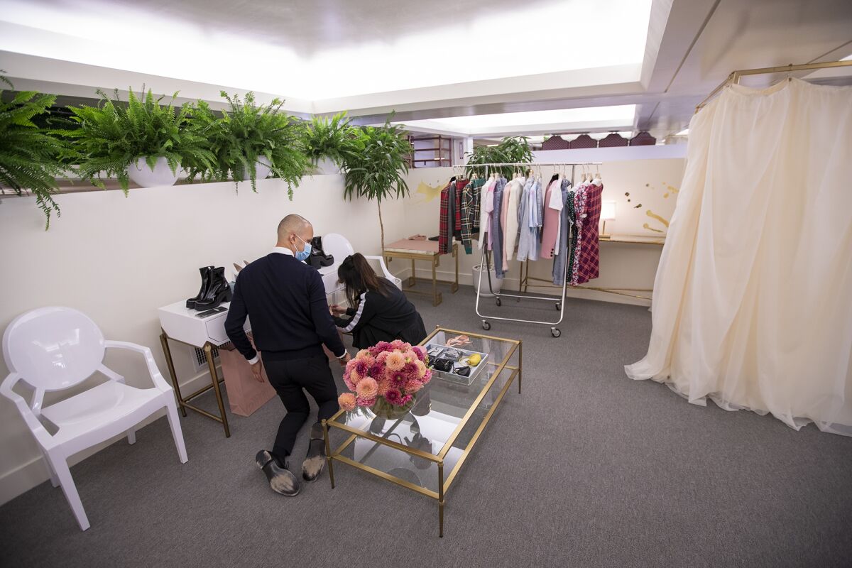 Rob Alvarez, left, and Katrina He, working for Miu Miu, prepare for a client at South Coast Plaza's the Pavilion on Friday.
