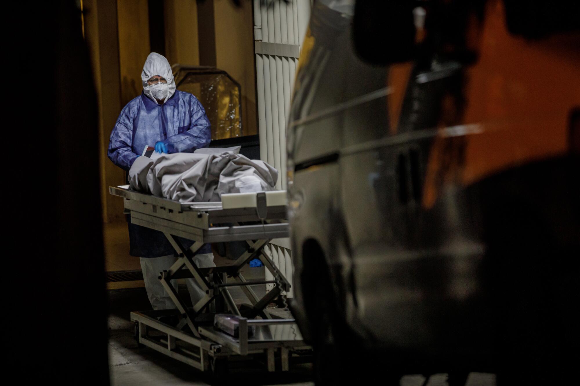A medical worker checks paperwork before handing off a corpse for transfer to a van that will bring it to the morgue, at Tijuana General Hospital, in Tijuana, Mexico, on April 25, 2020. Tijuana General Hospital is the largest hospital in Baja California and has been set aside to treat COVID-19 patients.