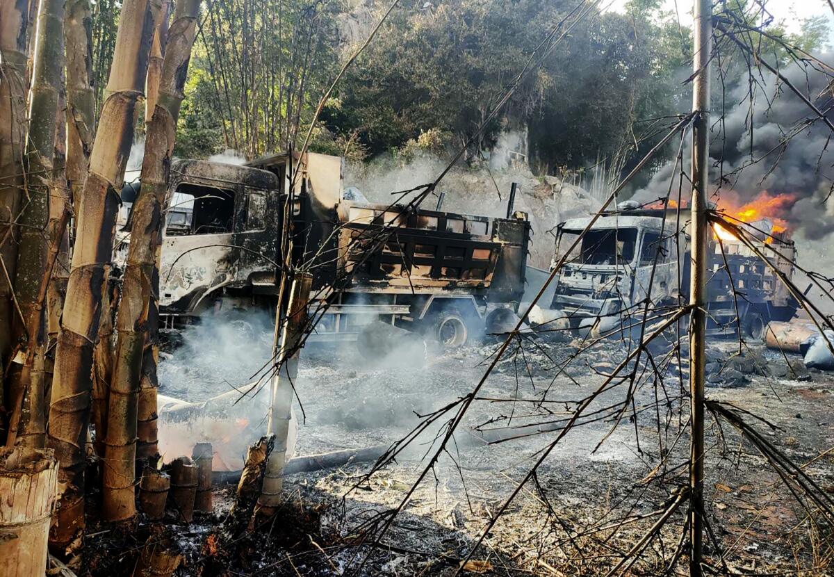 Smoke billows from several charred trucks.