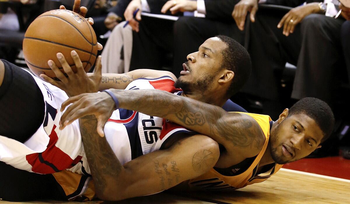 Wizards forward Trevor Ariza, left, looks to pass before Pacers forward Paul George can tie him up during a scramble for a loose ball in the second half of Game 6 on Thursday night in Washington.