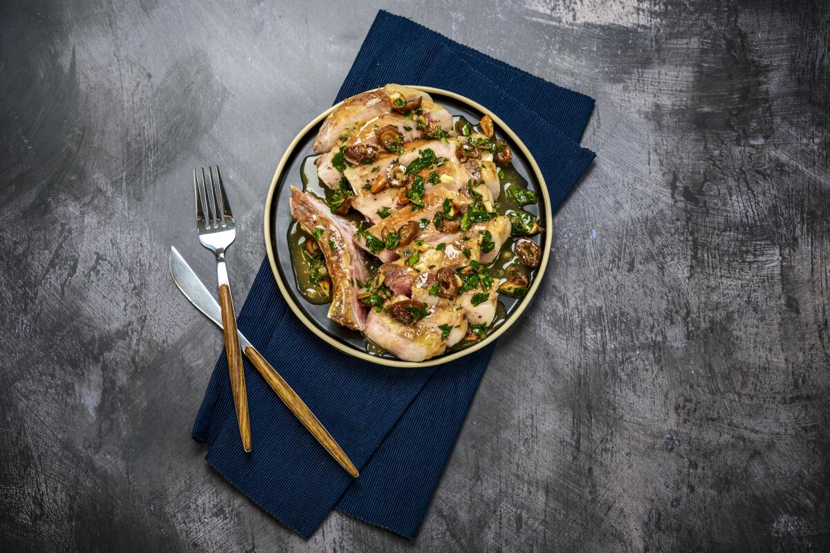 A fork and knife and a plate of pork, all atop a navy napkin