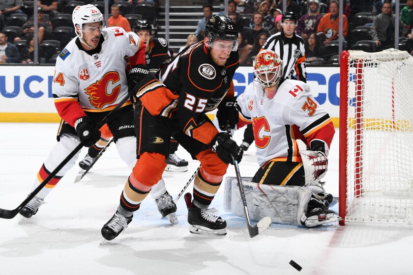 Ducks forward Ondrej Kase tries to control the puck in front of Flames goaltender Cam Talbot and defenseman Travis Hamonic during the Ducks' 2-1 loss Sunday.