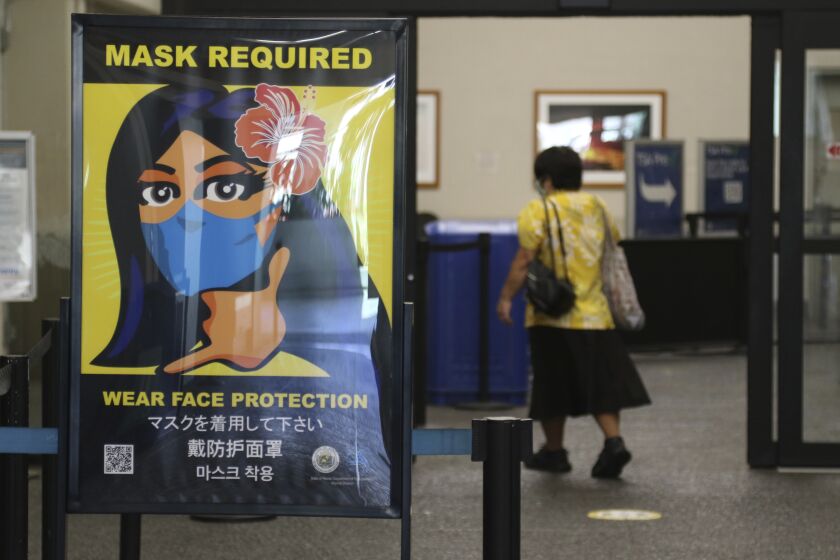 FILE - In this Oct. 2, 2020 file photo, a woman walks into the international airport in Honolulu amid a quarantine rule that effectively shut down the tourism industry in the state. A requirement that people on planes and other forms of transportation in the U.S. wear masks to prevent the spread of COVID-19 will remain in place through at least Sept. 13, the Transportation Security Administration said Friday, April 30, 2021 (AP Photo/Caleb Jones, File)