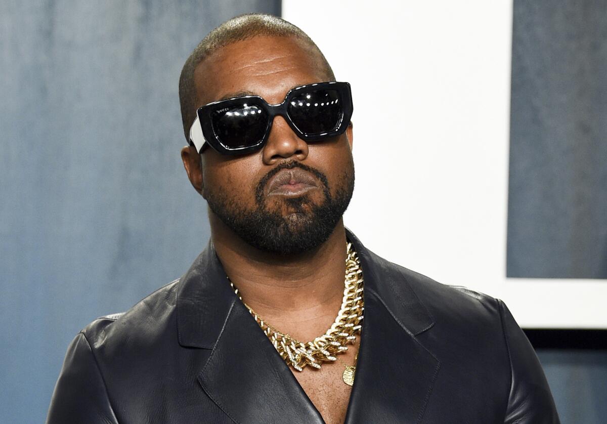 Kanye West poses for a picture on a red carpet.