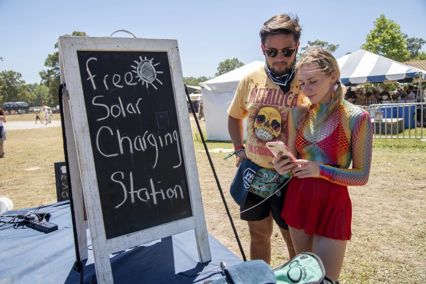 Asistentes al festival usan una estación de carga solar gratuita en el Festival de Música y Artes de Bonnaroo, el sábado 18 de junio de 2022 en Manchester, Tennessee. (Foto de Amy Harris/Invision/AP)