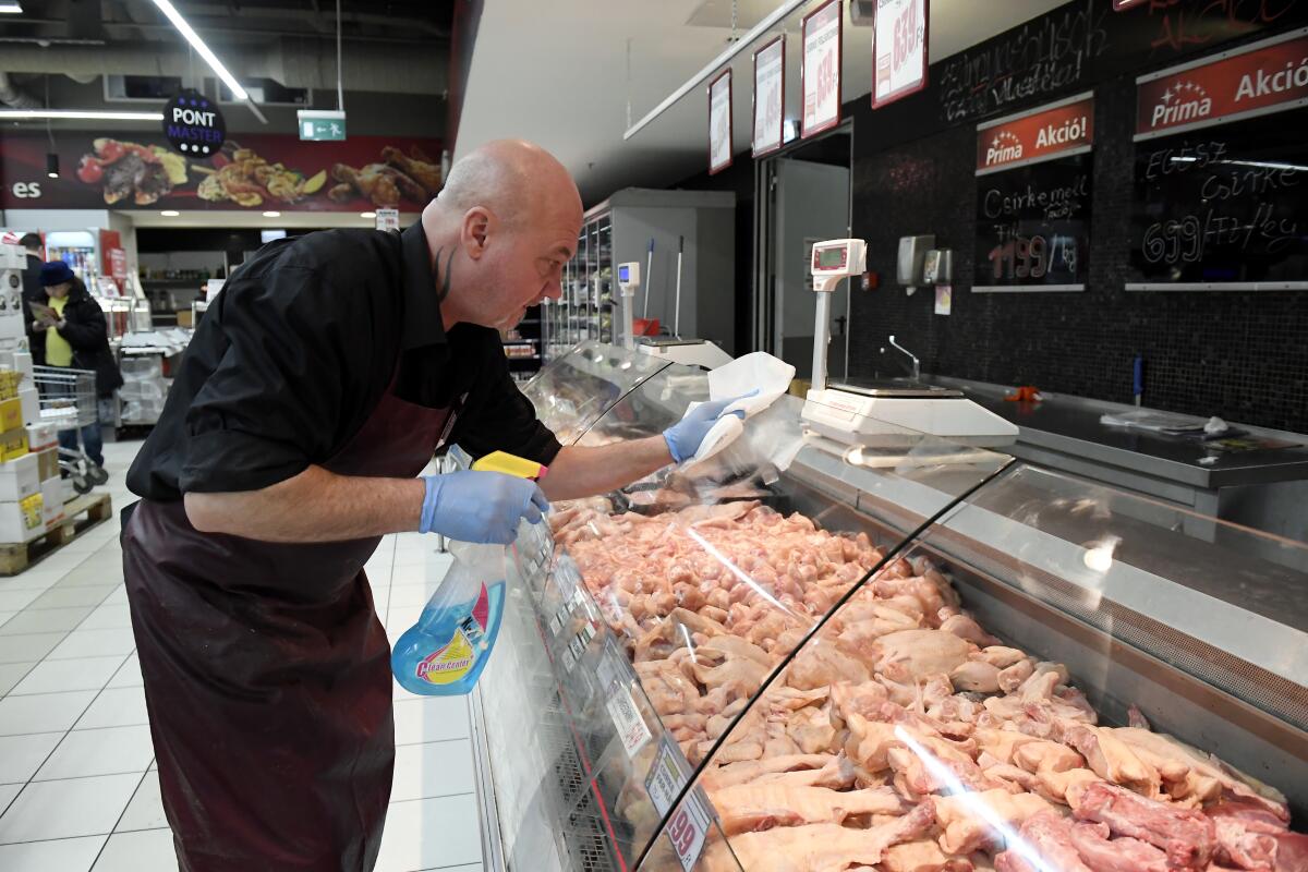 A grocery store employee disinfects the glass cover of a butcher counter to prevent the spread of the novel coronavirus in Budapest, Hungary.
