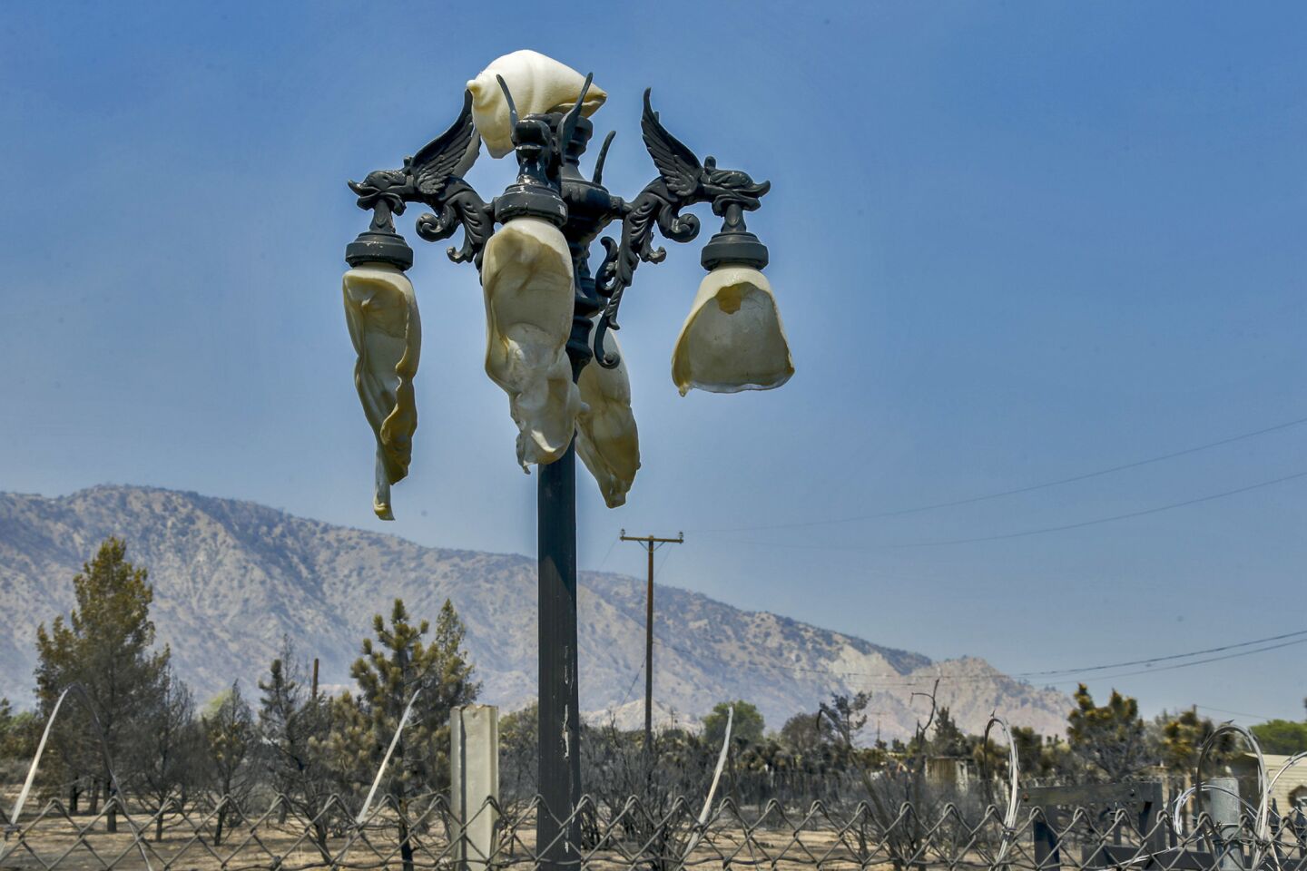 A light pole with plastic globes melted in the heat of the Blue Cut fire stands along Tamarind Avenue in Phelan.
